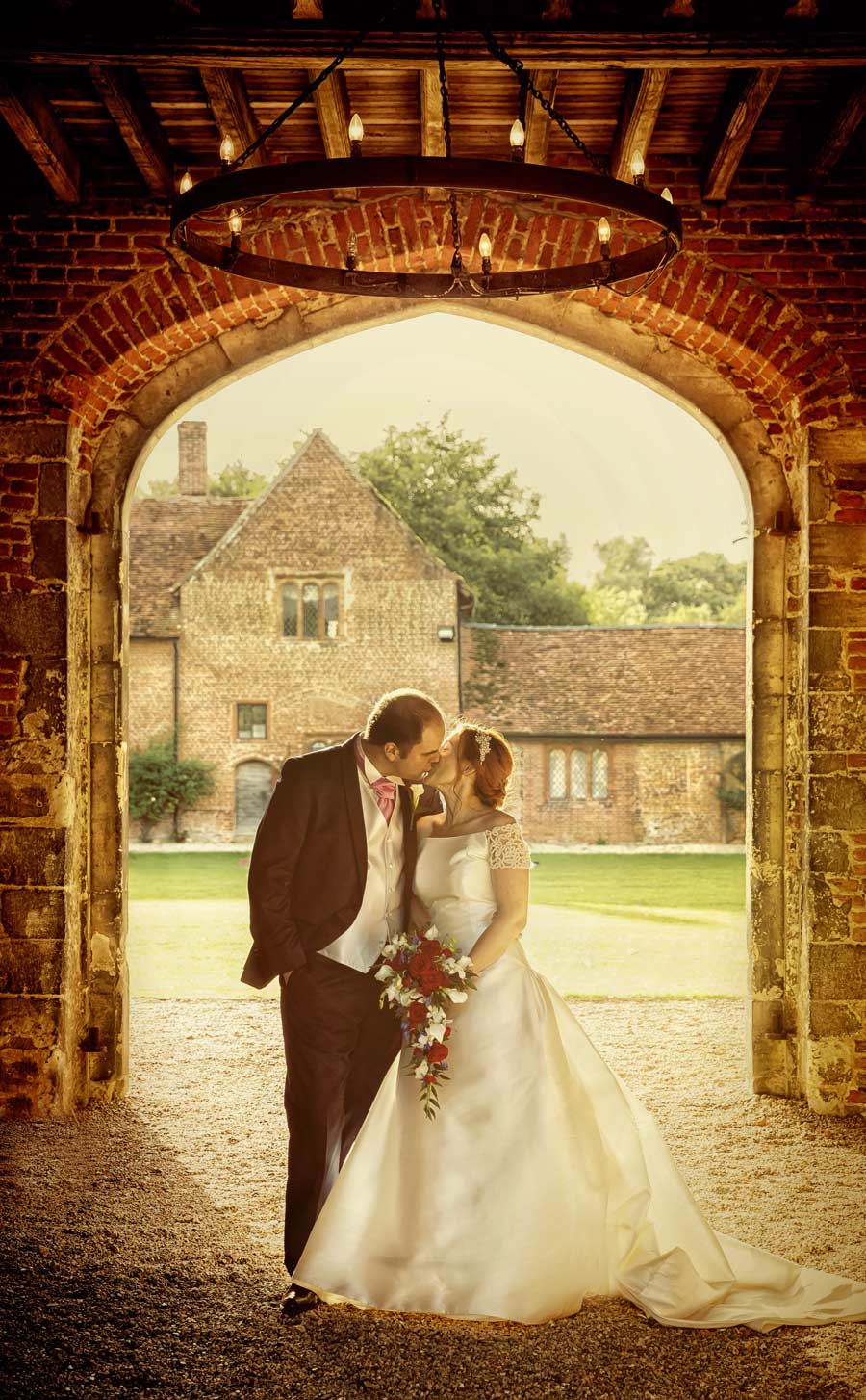 wedding couple kiss under arch at Leez Priory