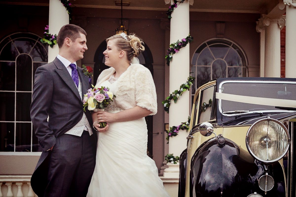 couple by wedding car outside Theobalds Park Hotel