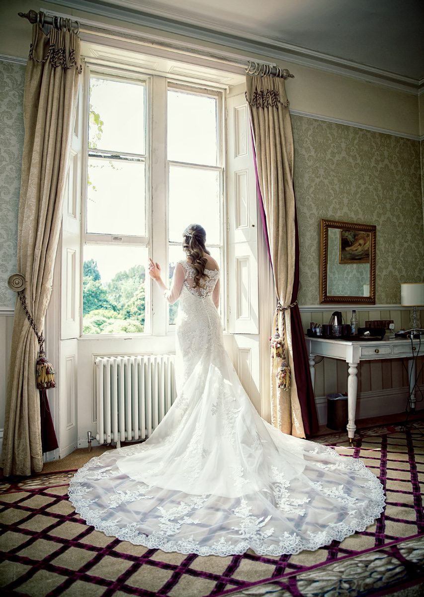 Bride looks out of window at her Shendish Manor wedding