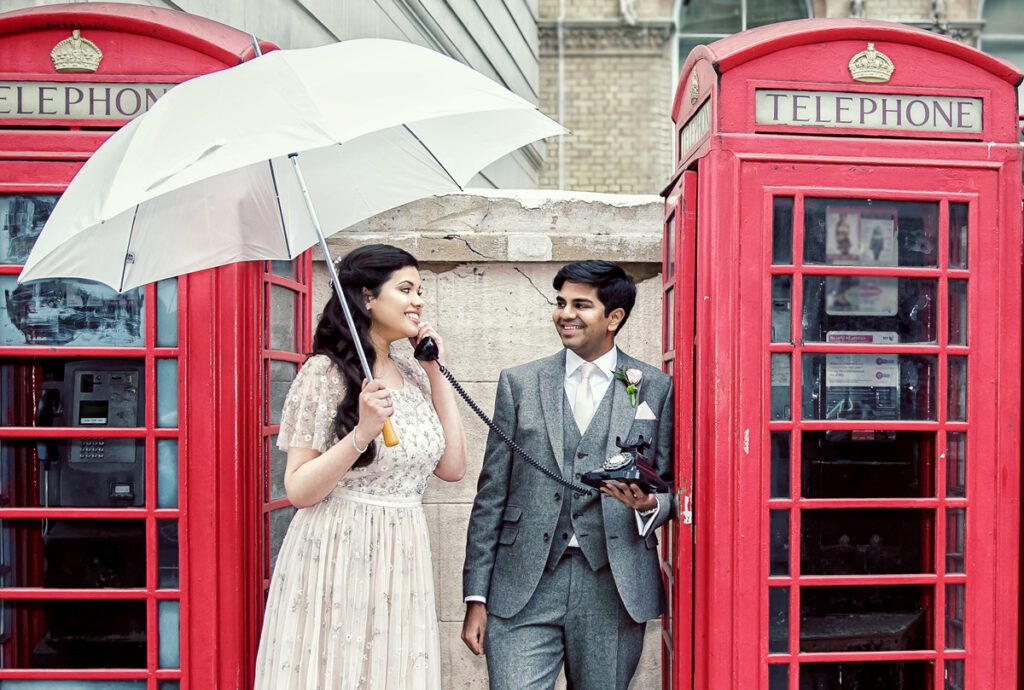 Langham Hotel wedding couple by red London telephone boxes with umbrella