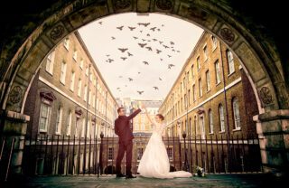 London wedding couple under arch with flying birds photo