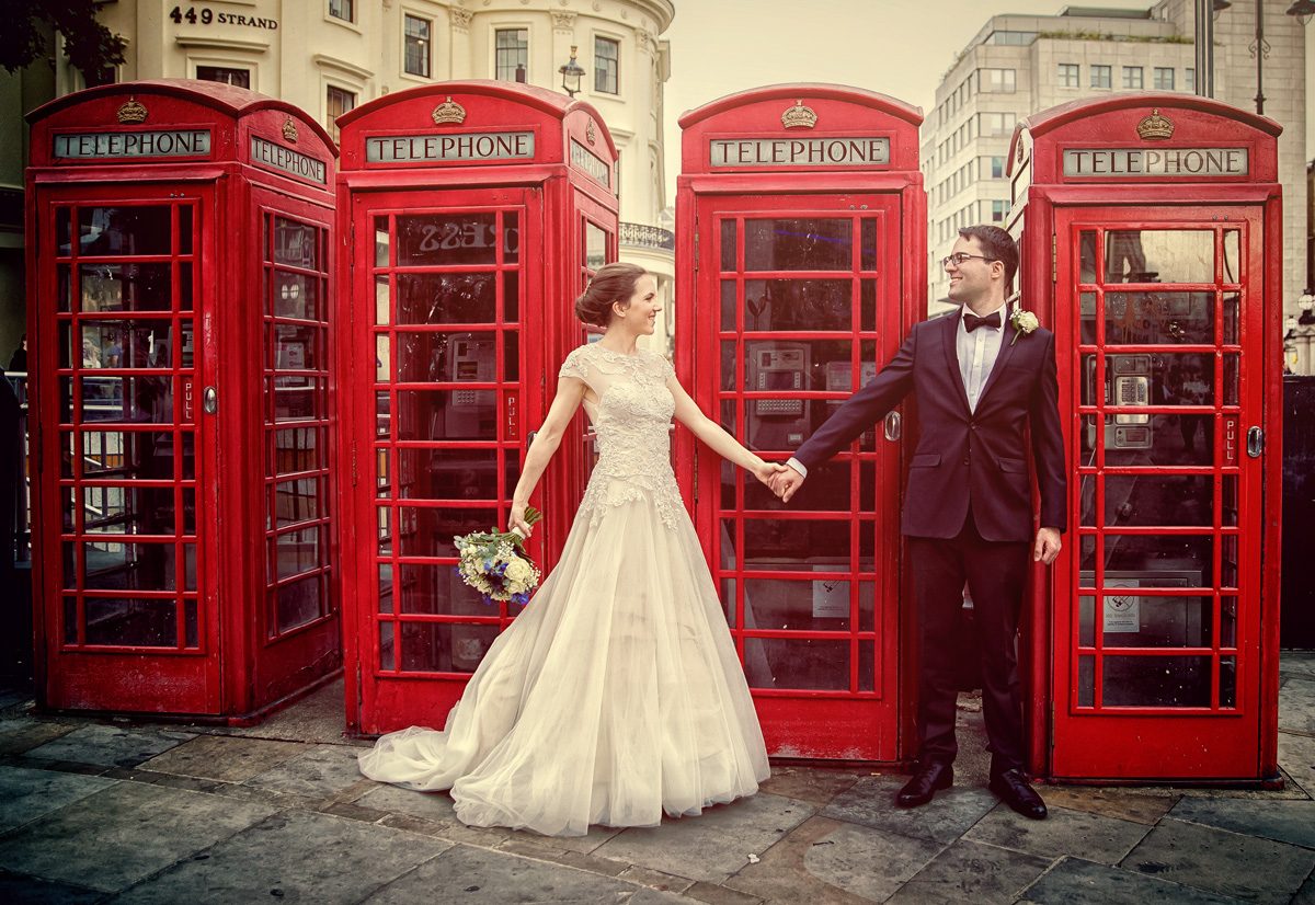 Wedding couple hold hands by London phone boxes Charing Cross