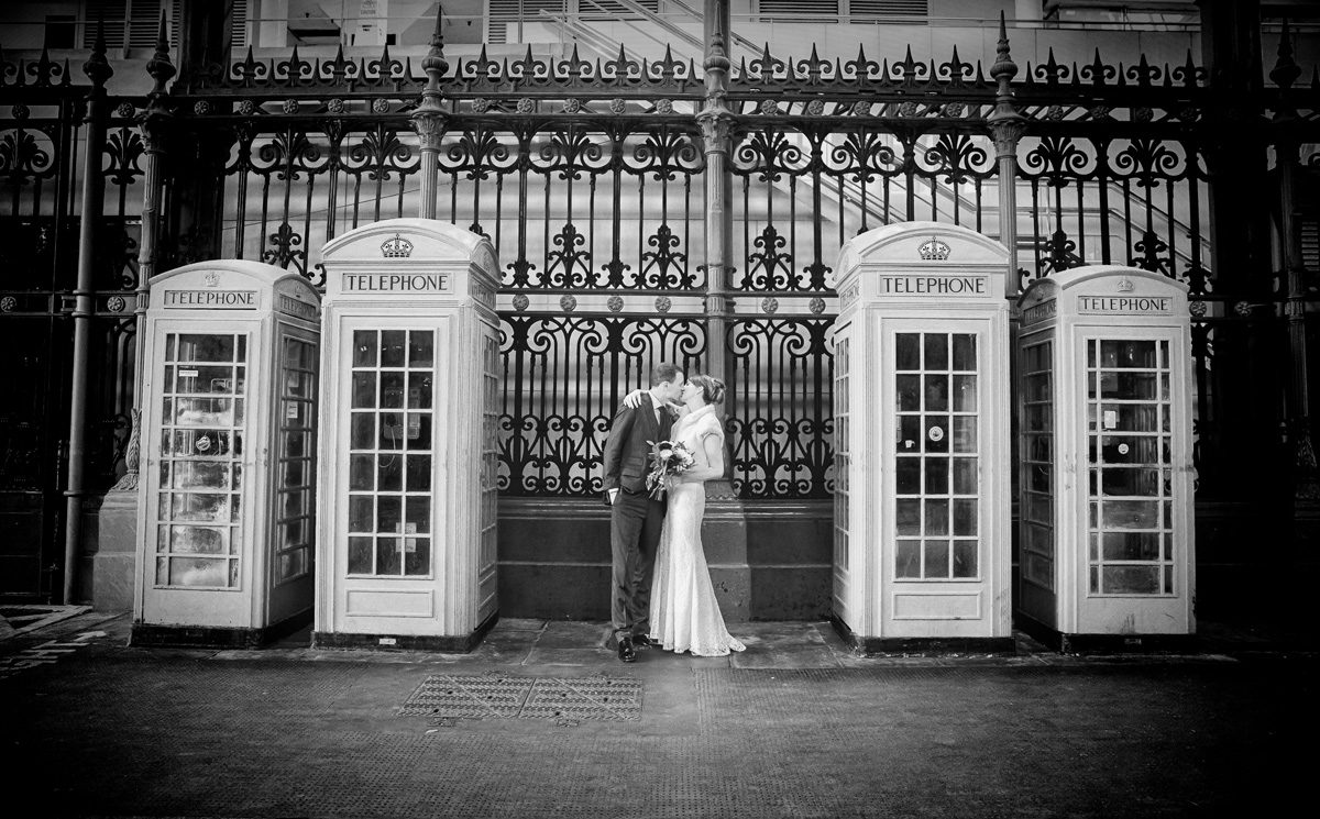 Bride and groom kiss by Smithfield Market phone boxes