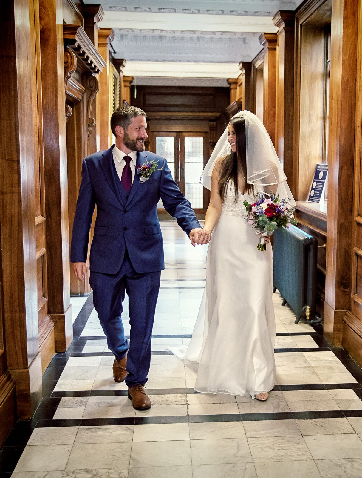 Bride and groom walk through Old Marylebone Town Hall corridor