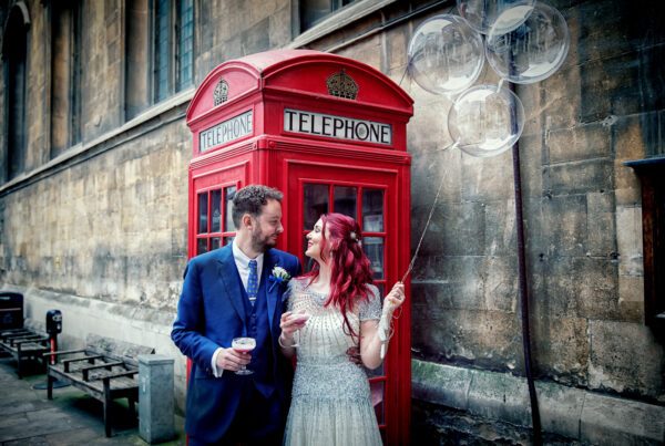 London wedding couple with balloons by red phone booth wide